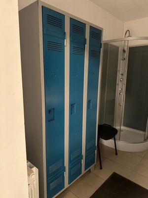 un casier bleu dans une salle de bains, à côté d'une douche