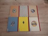 four notebooks sitting on top of a wooden floor next to each other