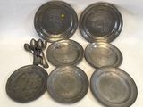 several silver plates and spoons on a white surface with a yellow dot