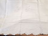 des nappes brodées posées sur une table en bois recouverte d'une nappe blanche