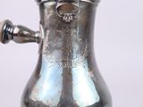 a silver coffee pot with a handle on a table