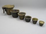un ensemble composé de cinq tasses en laiton et d'un récipient en laiton