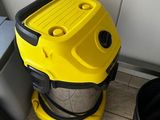 a yellow and black vacuum sitting on the floor next to a trash can