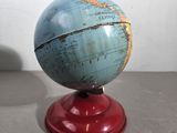 un petit globe bleu posé sur un socle rouge, sur une table
