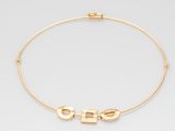 un collier ras-du-cou en or sur lequel est gravé le mot « she »