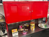 an image of a kitchen with a red cabinet and a green chair