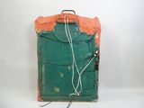 une vieille valise munie d'une cordelette, posée sur une surface blanche