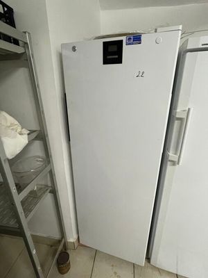 a white refrigerator next to a metal shelf in a kitchen