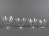 six glass goblets are lined up in a row on a gray surface