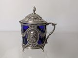 an antique silver and blue glass teapot on a white surface