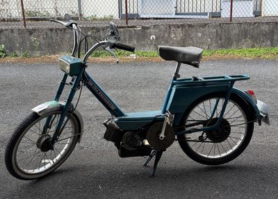 a small blue bike parked on the side of the road