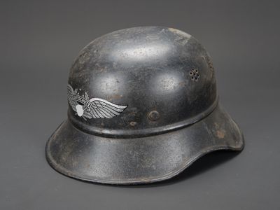 un vieux casque orné d'un emblème ailé sur fond gris