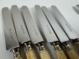 six knives are lined up on a table with a knife in front of them