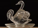 a glass sculpture of a swan on a glass plate