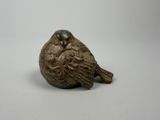 un gros plan d'une figurine d'oiseau posée sur une surface blanche