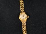 an image of a gold wrist watch with a chain around it