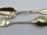 two silver spoons and a spoon on a white surface