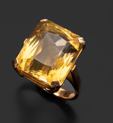 un gros plan d'une bague ornée d'une pierre jaune sur un fond noir