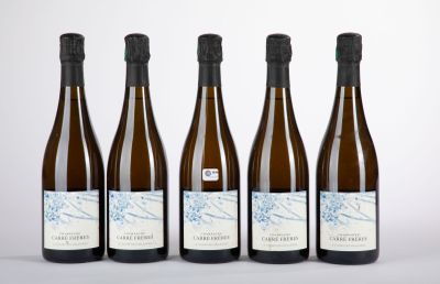 quatre bouteilles de vin sont alignées sur une surface blanche