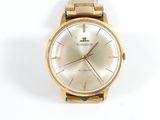 a gold watch on a white surface with a white background