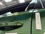 a measuring tape on the door handle of a green car