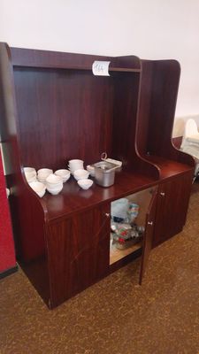 a small wooden cabinet with bowls and cups on it