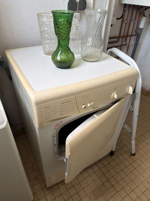 a green vase on top of a washer and dryer