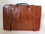 brown leather briefcase sitting on a white surface with a white background