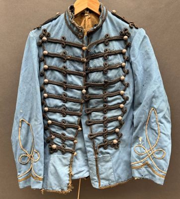une vieille veste militaire bleue à boutons dorés, suspendue à un cintre