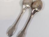 two spoons that are sitting next to each other on a table