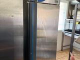 a person that is pointing at a stainless steel refrigerator