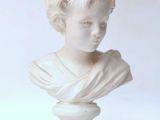 white marble bust of a young boy with curly hair on a pedestal