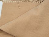 two pieces of tan fabric with fringes on a white surface