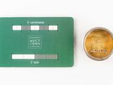 a green card and a gold coin on a white surface