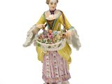 two porcelain figurines of a woman with a basket of flowers