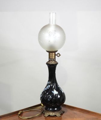 une lampe noire et blanche posée sur une table en bois près d'un mur blanc