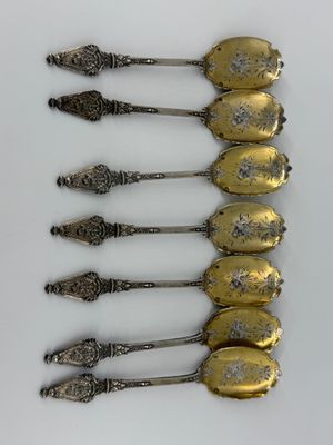 six silver spoons are lined up in a row on a white surface