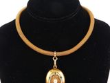 necklace with a gold and green pendant on a black mannequin