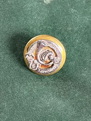 un bouton en argent et en or sur lequel est représenté un homme