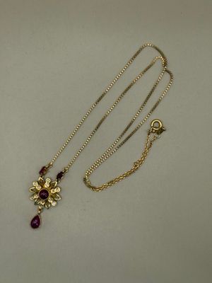 a close up of a necklace with a flower on it