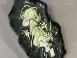 a piece of black rock with white flowers on it