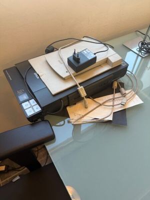 une table en verre sur laquelle se trouvent une imprimante et un téléphone portable