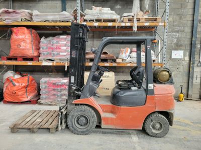 a forklift in a warehouse with a lot of items on the shelves