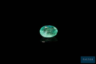 a close up of a green diamond on a black surface