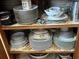 many plates and cups stacked on a shelf in the kitchen