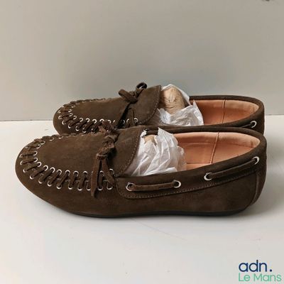 une paire de mocassins en daim marron posés sur une surface blanche