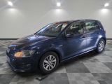Une Volkswagen Golf bleue est garée dans une pièce au sol à carreaux.