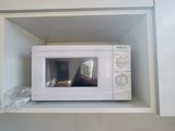 un micro-ondes blanc posé sur une étagère au-dessus d'un évier