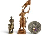 une petite statue représentant une femme tenant un drapeau à côté d'une pièce de monnaie