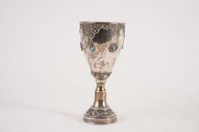 une tasse en argent posée sur une surface blanche